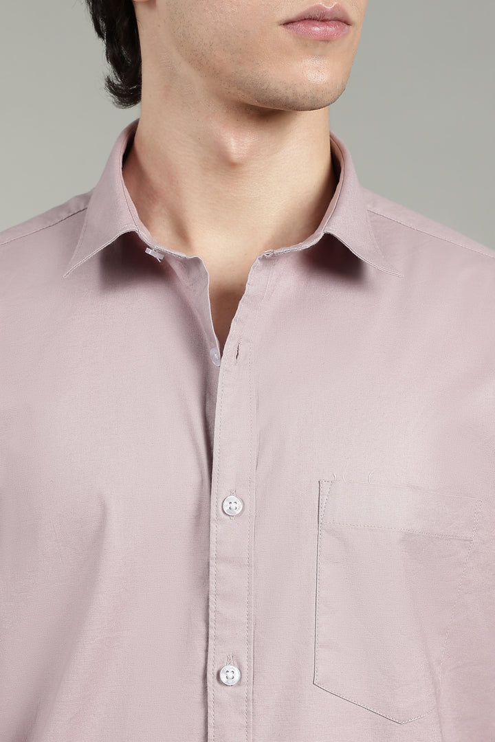 Close-up of a mute pink shirt worn by a man on a gray background