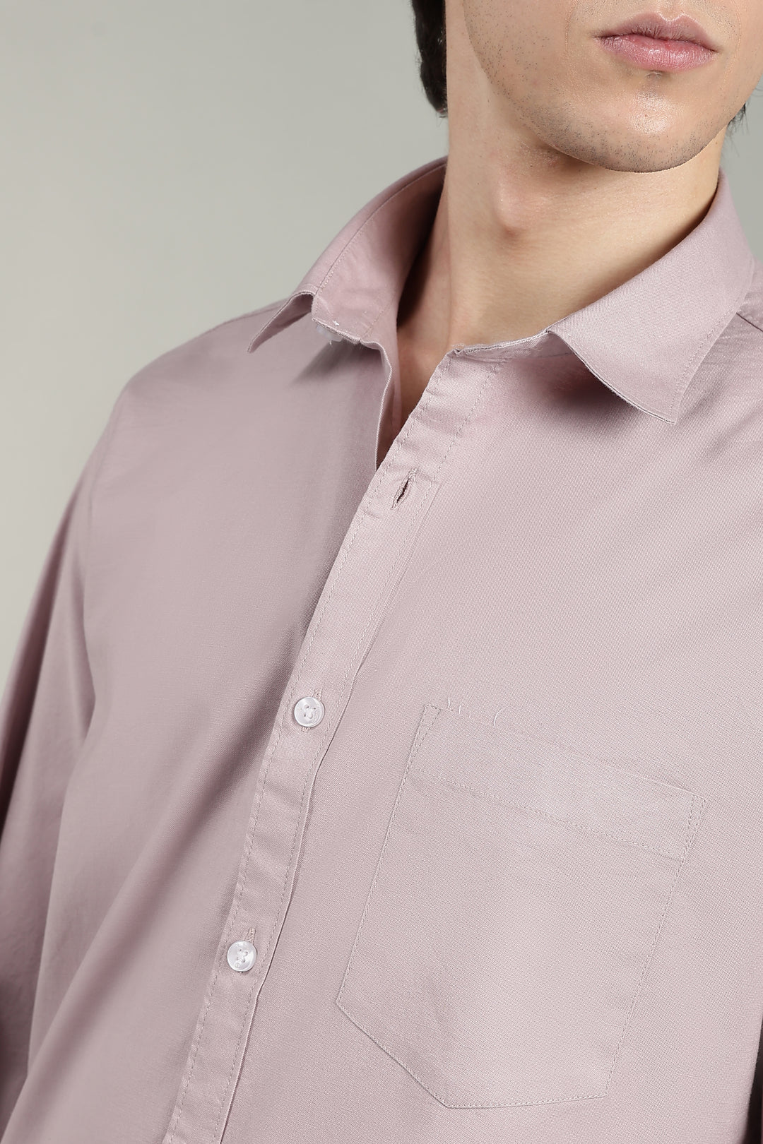 Close-up of a person wearing a mute pink shirt against a neutral background