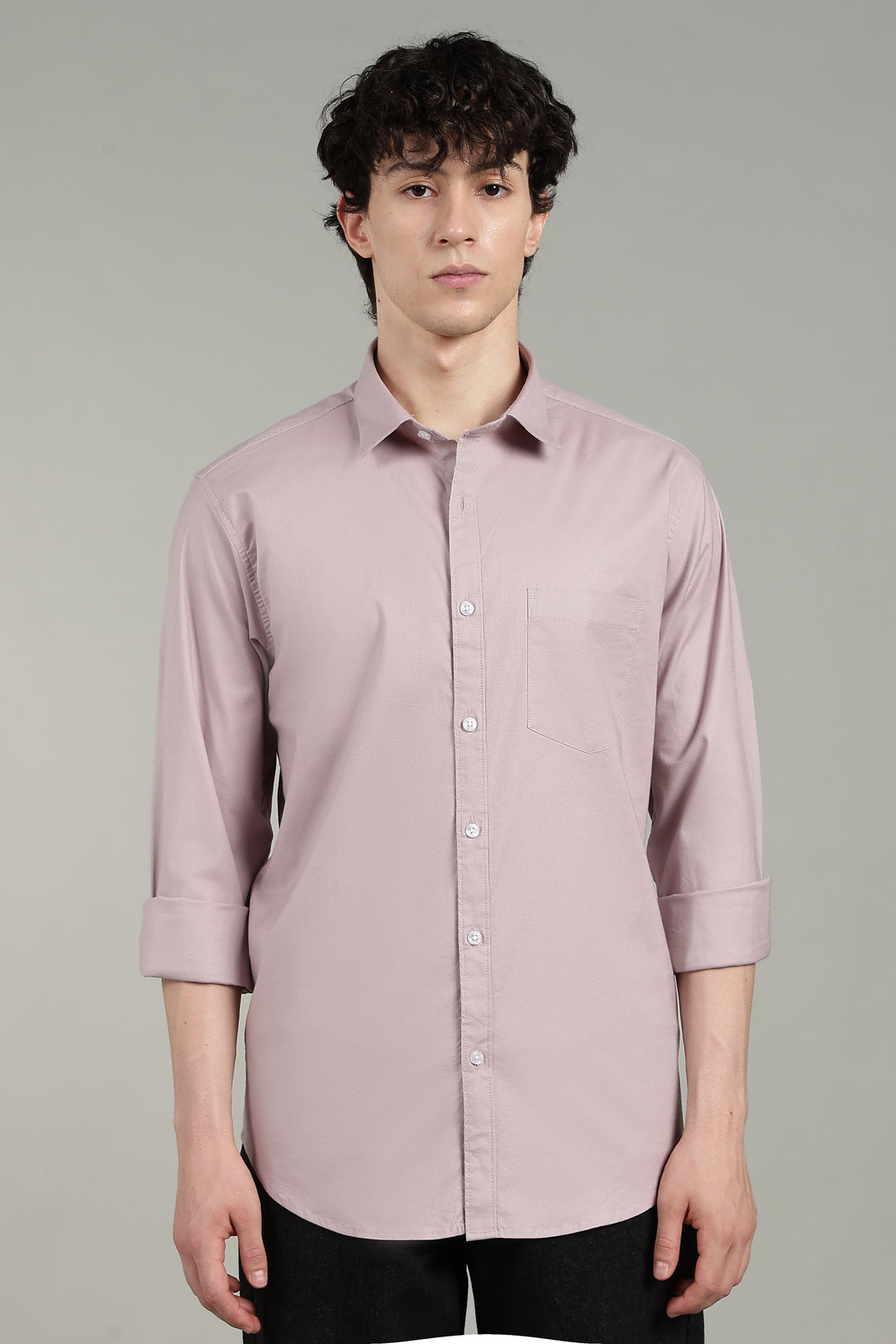 man wearing a mute pink button-up shirt against a gray background