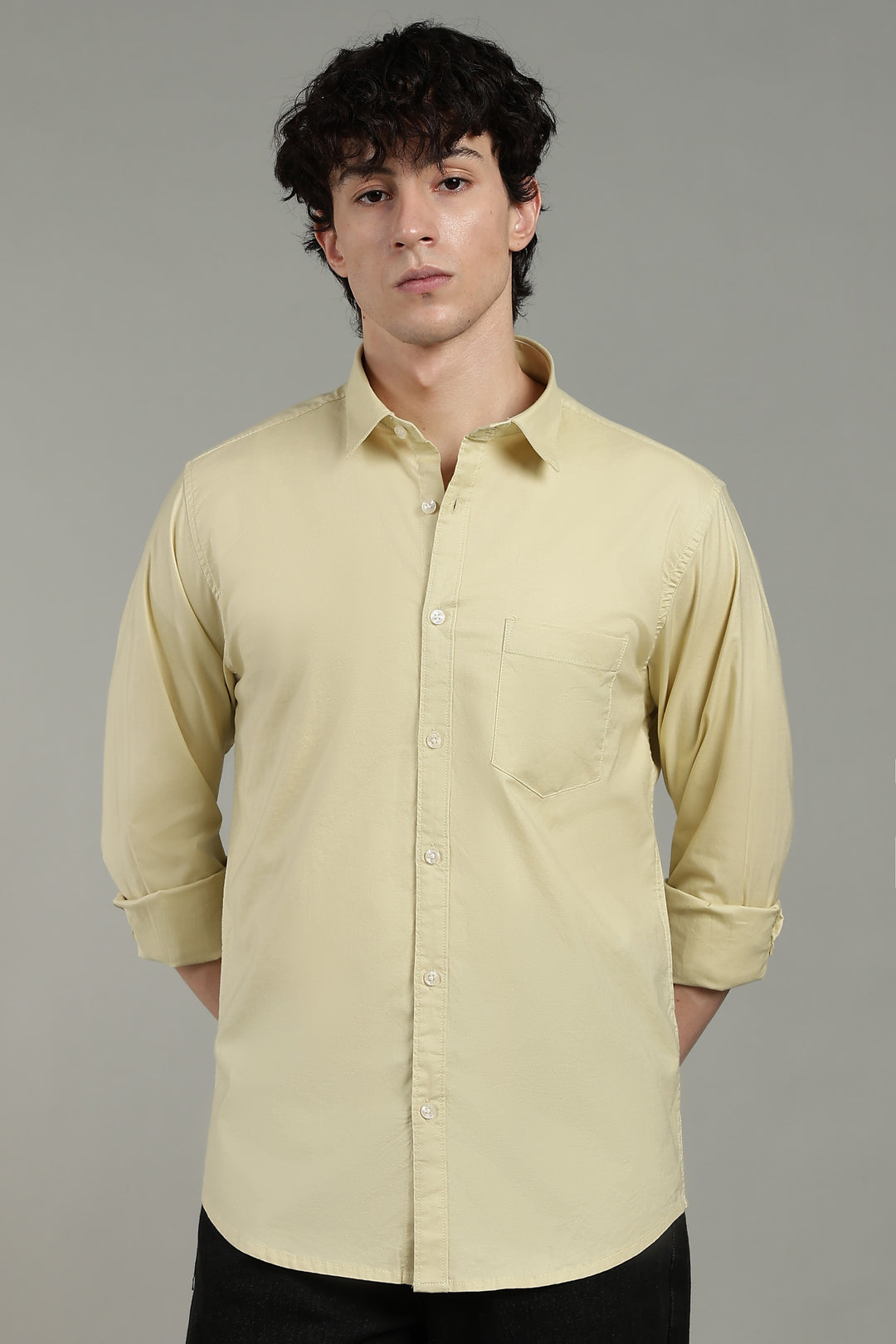 Man wearing a light yellow shirt against a gray background
