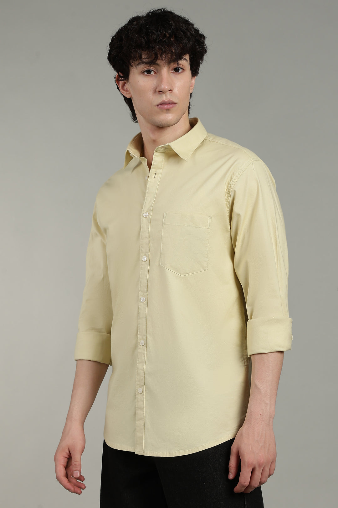Man wearing a light yellow shirt against a gray background