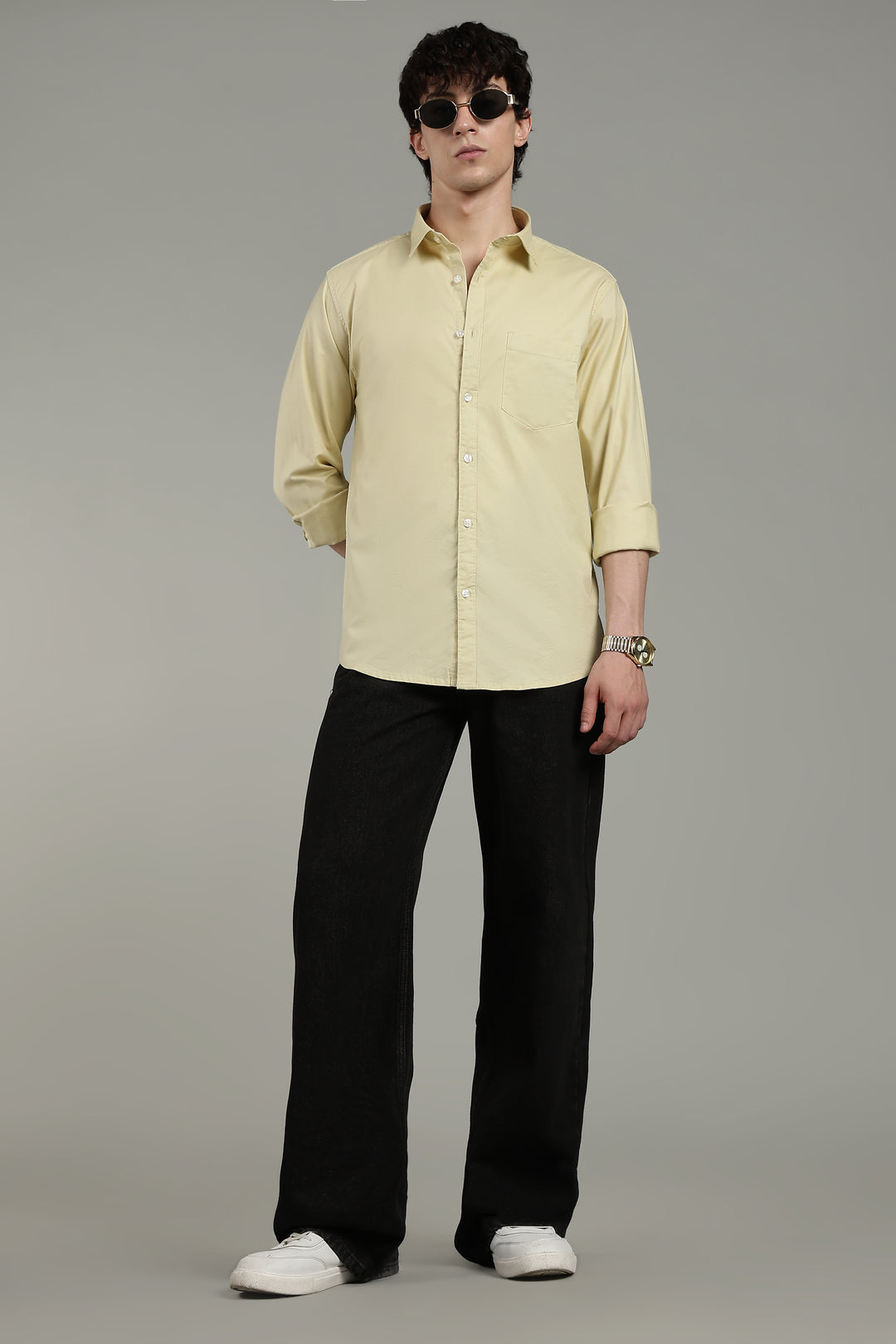 Man wearing a light yellow shirt and black pants on a gray background