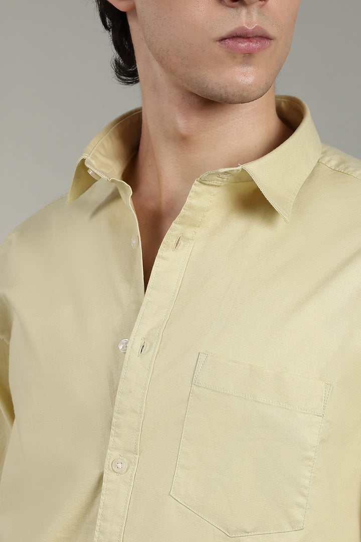 Close-up of a man wearing a light yellow shirt with a neutral background
