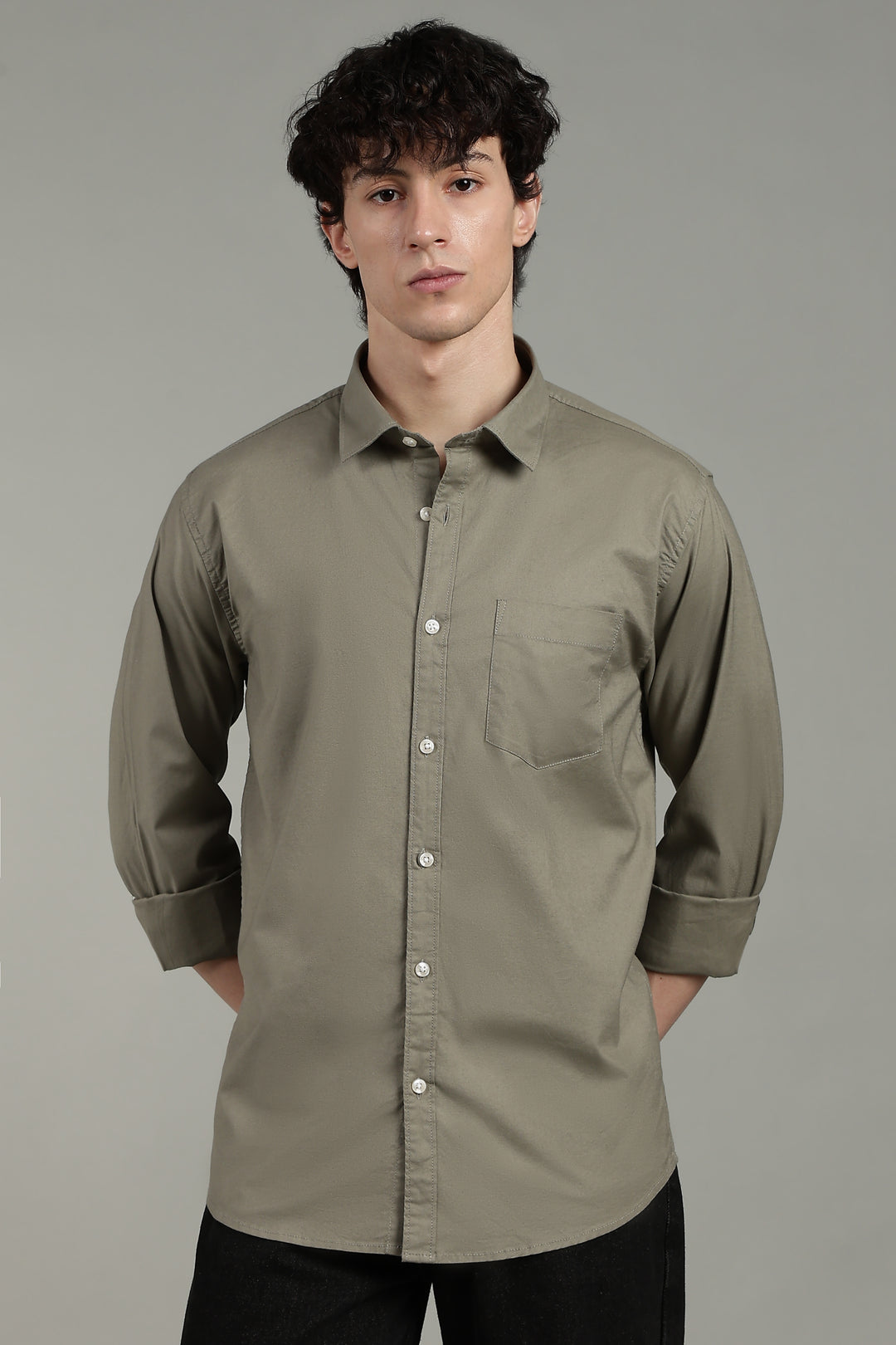 Man wearing a sage green button-up shirt against a gray background
