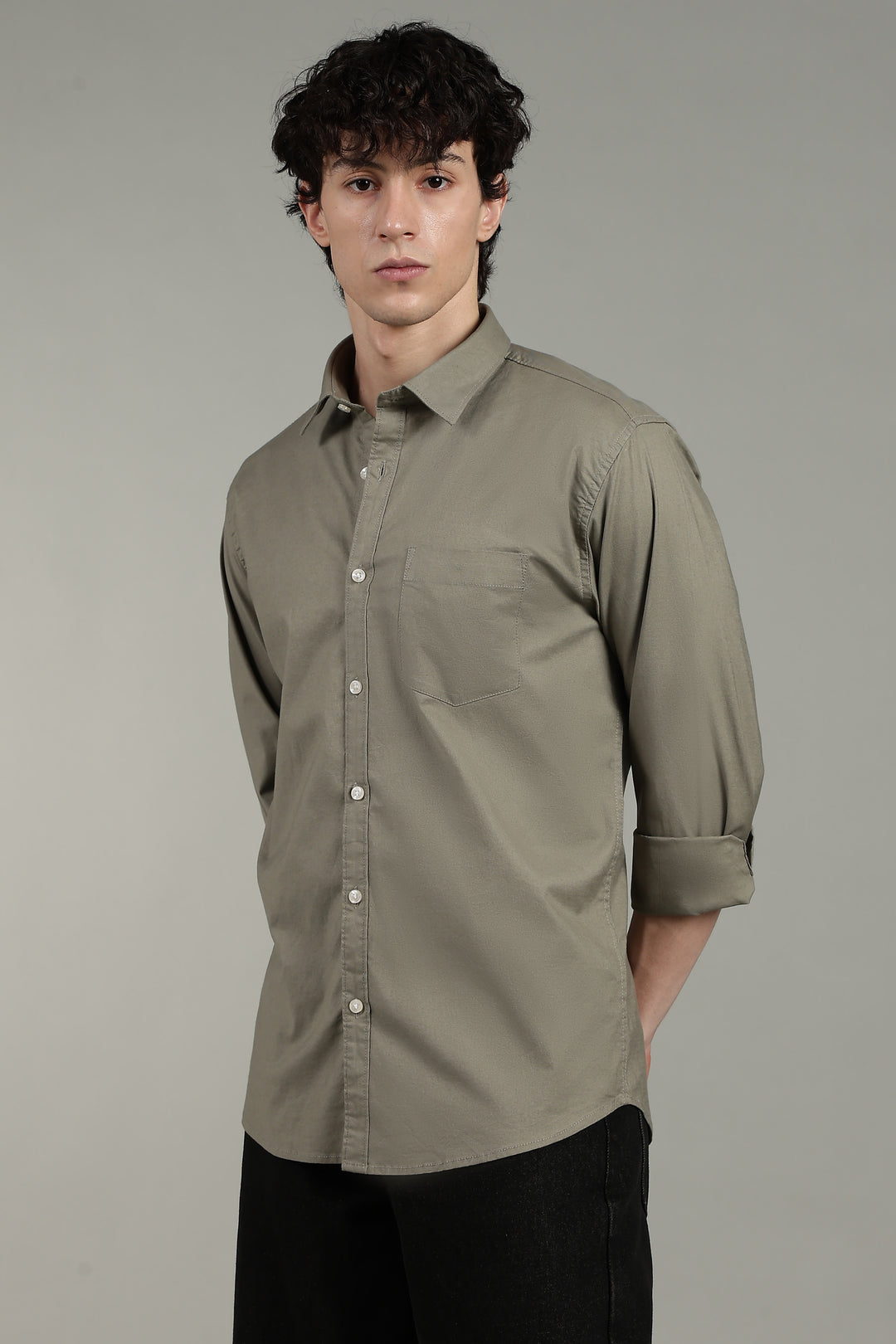 Man wearing a sage green button-up shirt against a gray background