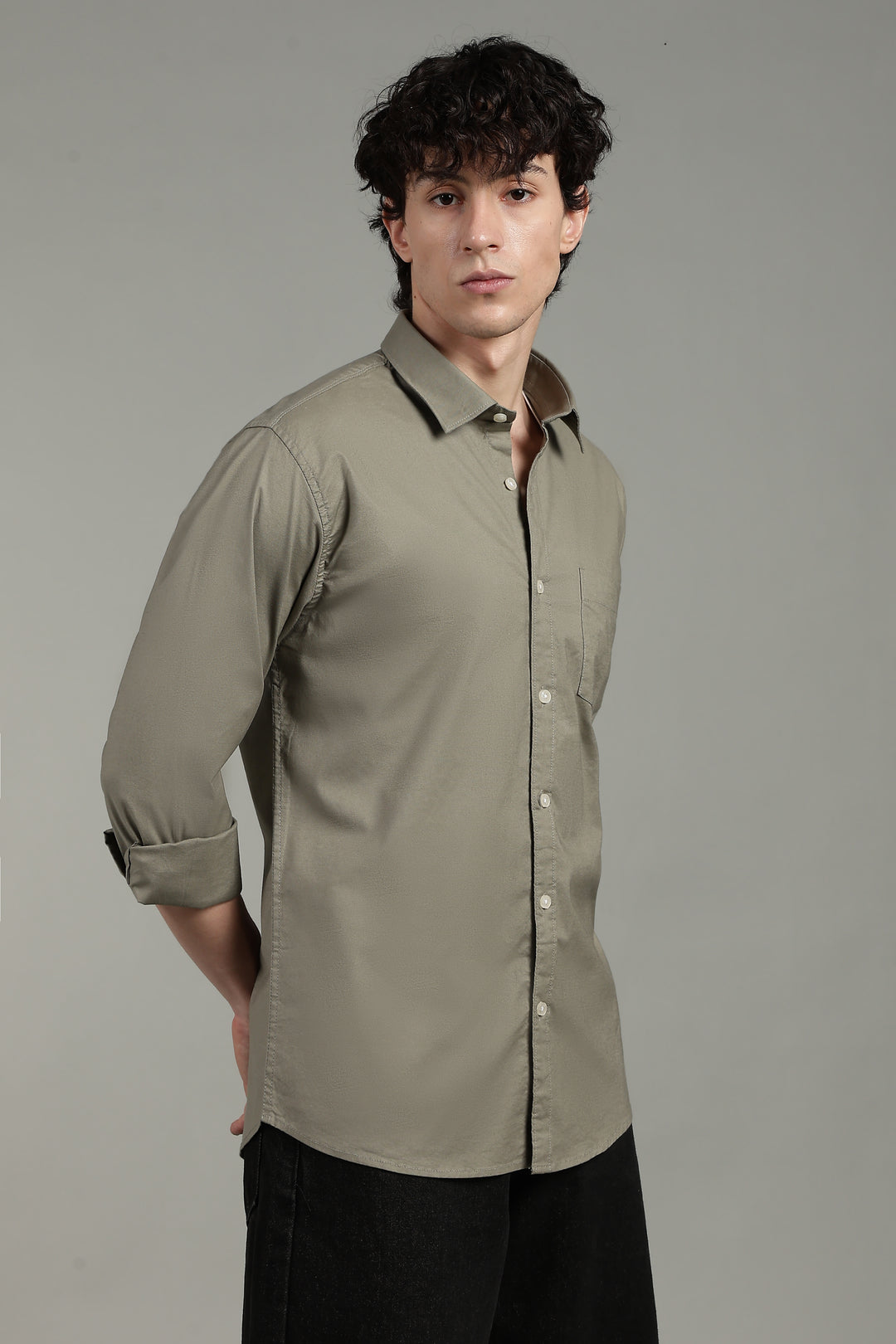 Man wearing a sage green dress shirt with black trim on a gray background