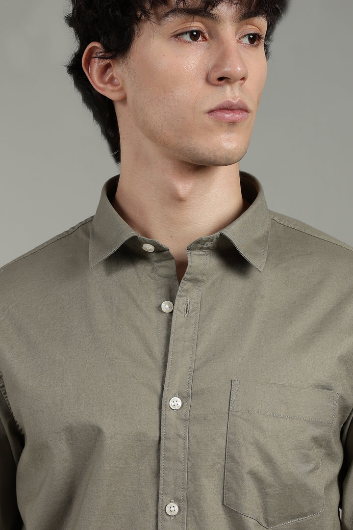Man wearing a sage green button-up shirt against a gray background
