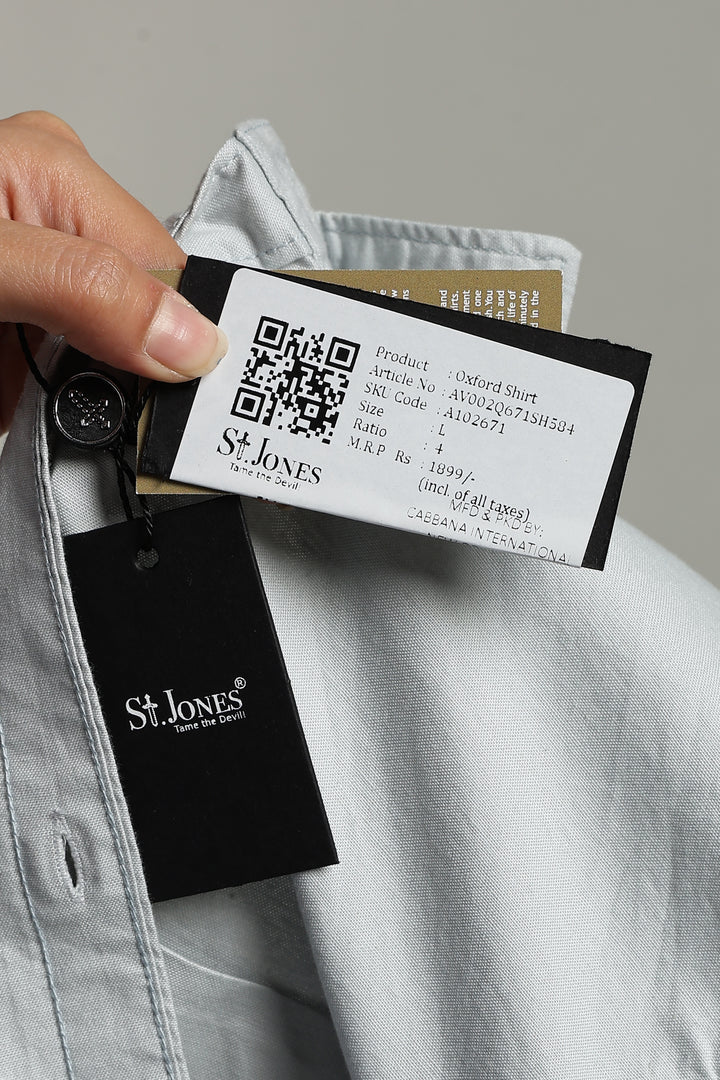 man holding a St. Jones label with a QR code on a gray background