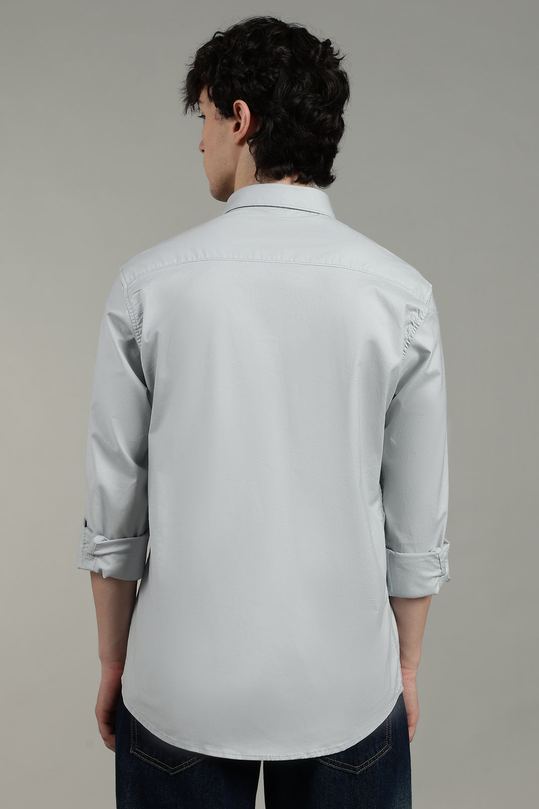 man wearing a icy blue shirt against a plain background