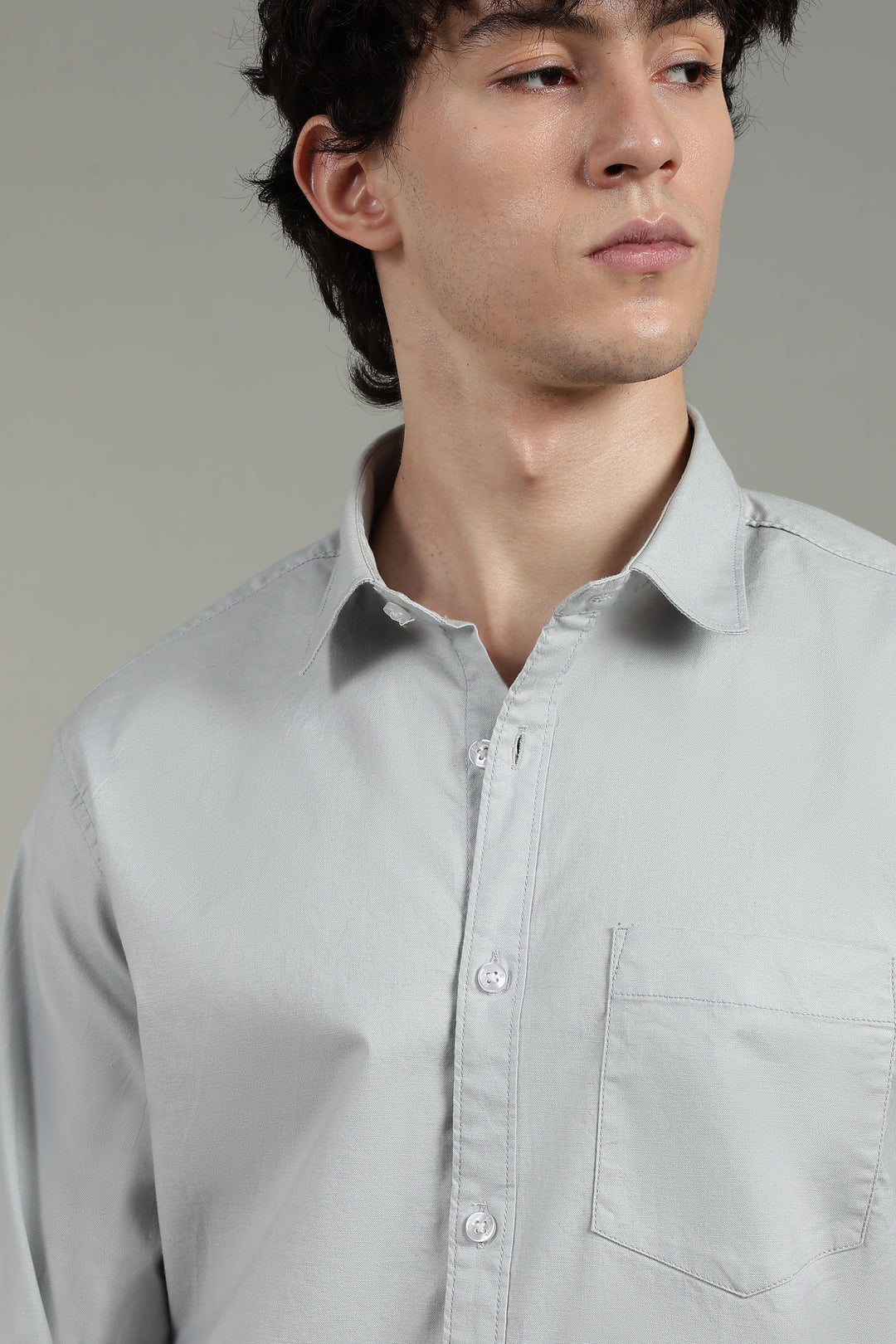 Man wearing a icy blue shirt against a neutral background