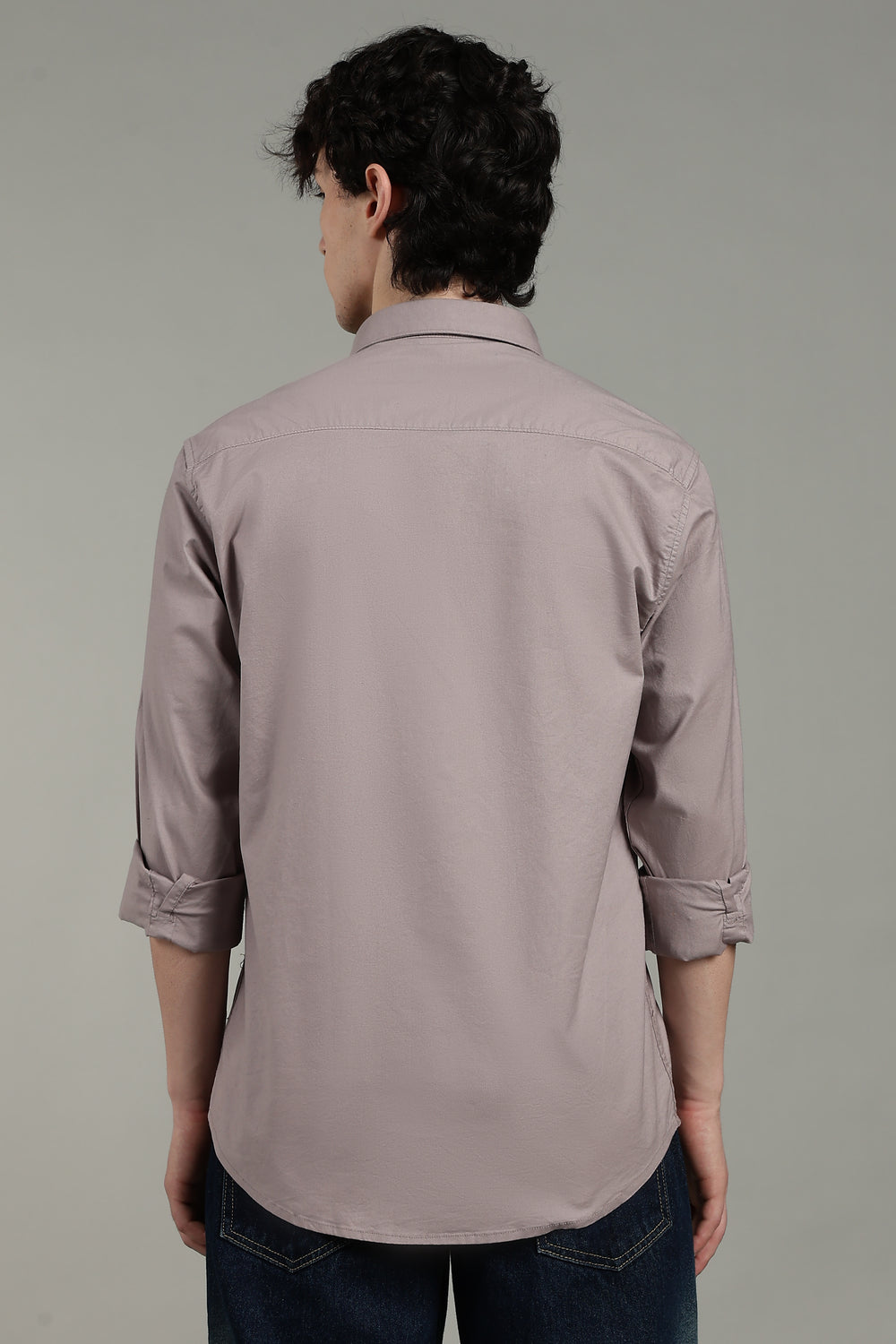 man wearing a light mink shirt with rolled-up sleeves on a gray background