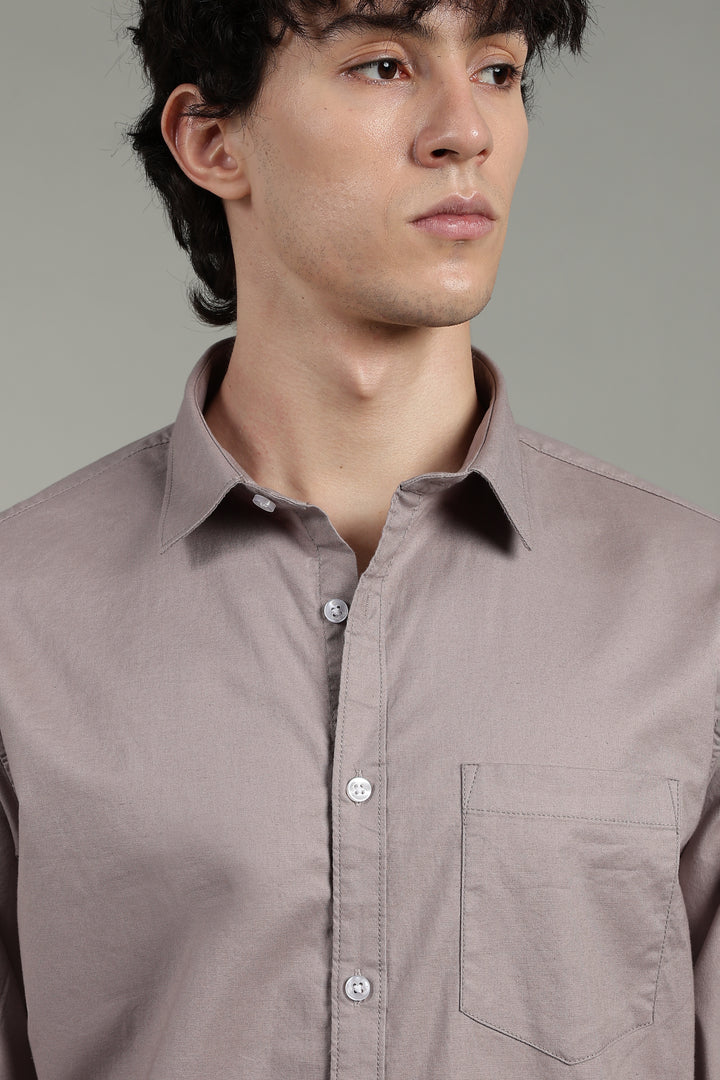 Man wearing a light mink button-up shirt against a gray background