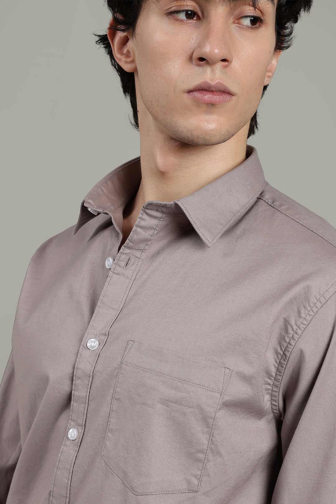 Man wearing a light mink shirt against a gray background
