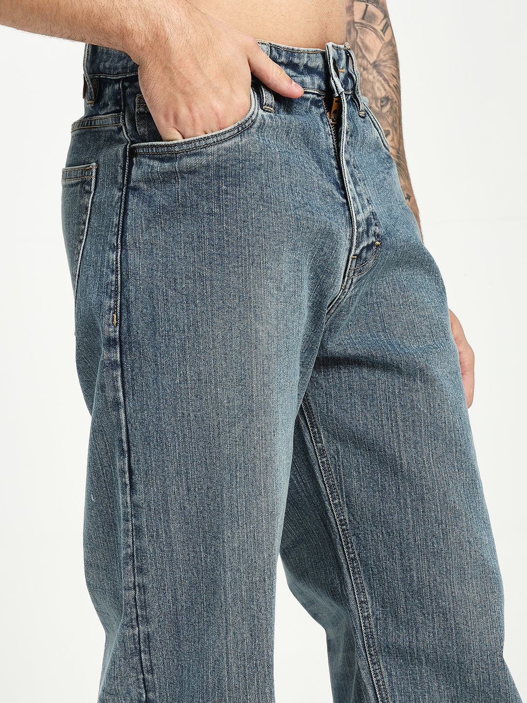 man wearing blue jeans with a tattooed arm on a white background