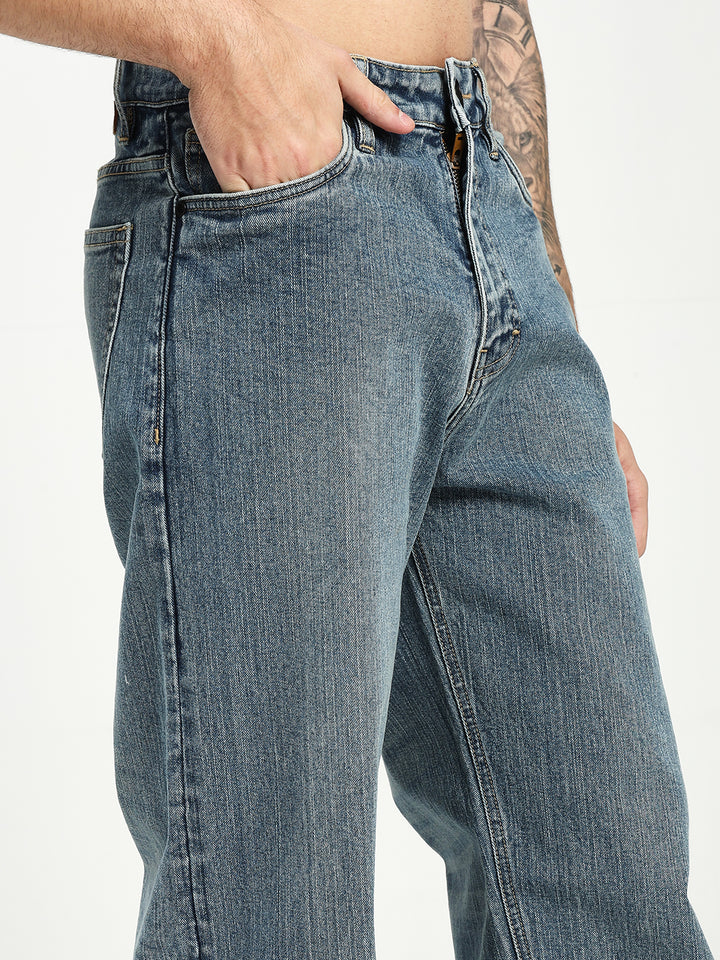 man wearing blue jeans with a tattooed arm on a white background