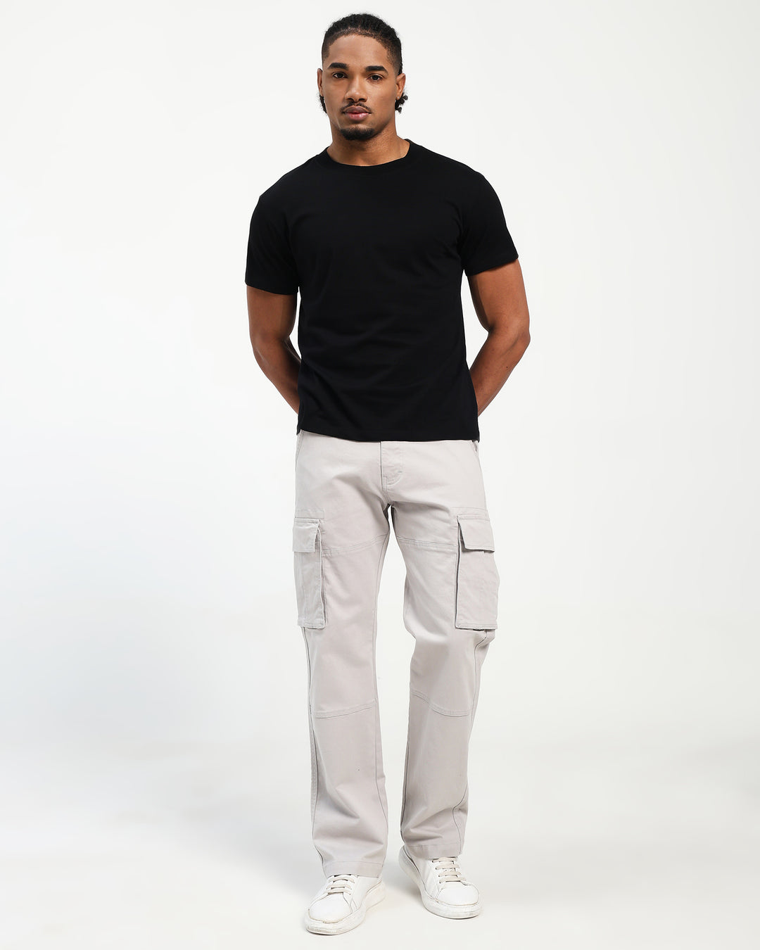 Man wearing a black t-shirt and light gray cargo pants on a white background