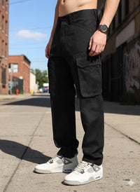 man wearing black camouflage cargo pants and white sneakers on a street.