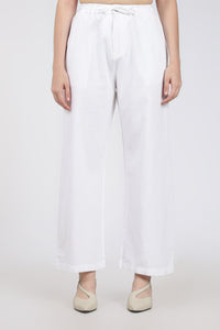 woman wearing white wide-leg pants on a plain background