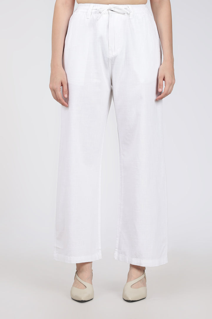 woman wearing white wide-leg pants on a plain background