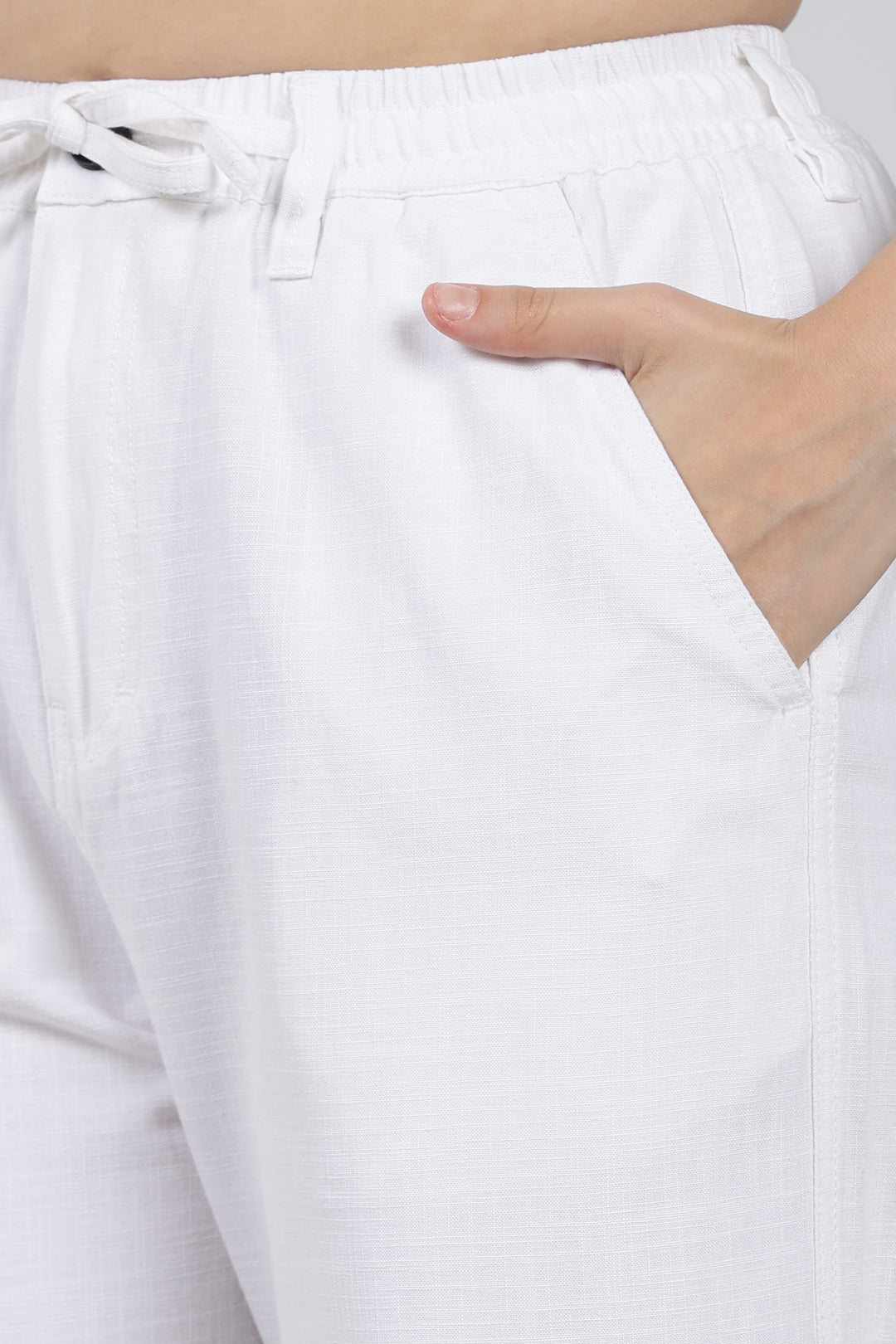 White pants with a hand in the pocket on a light background