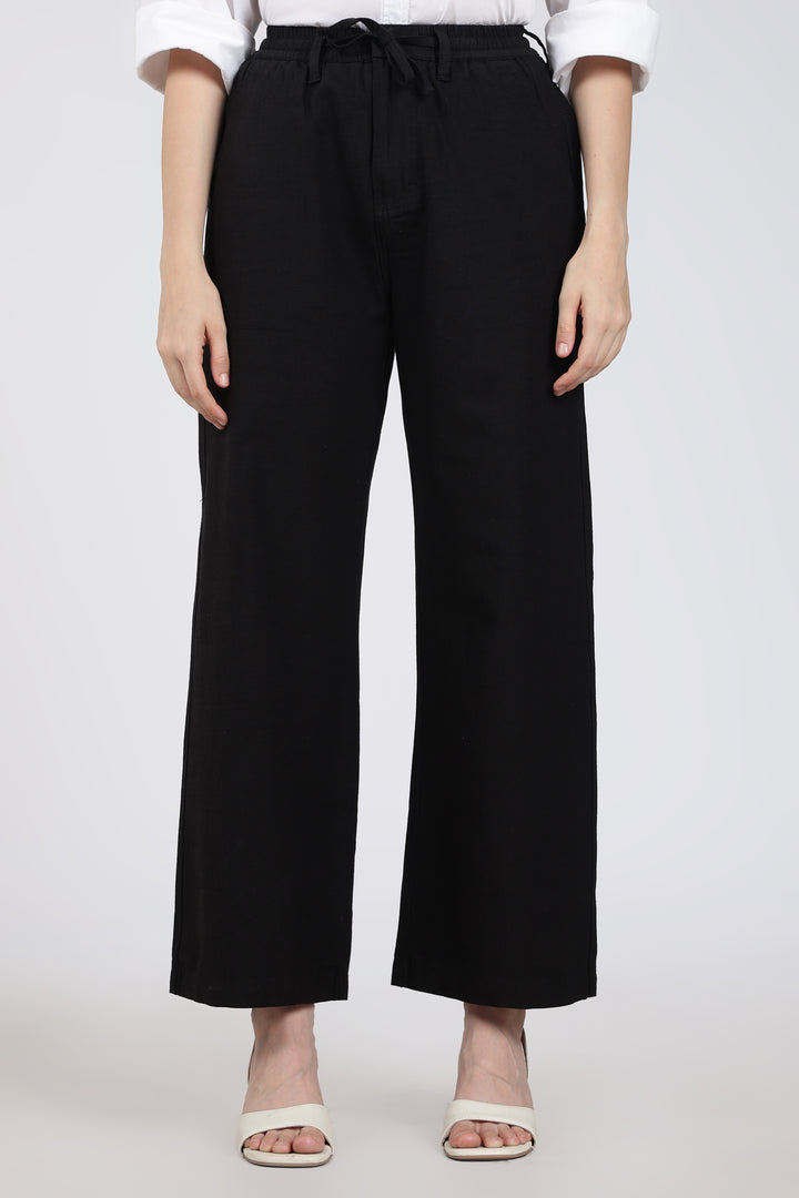 woman wearing black wide-leg pants with a tie waist on a white background