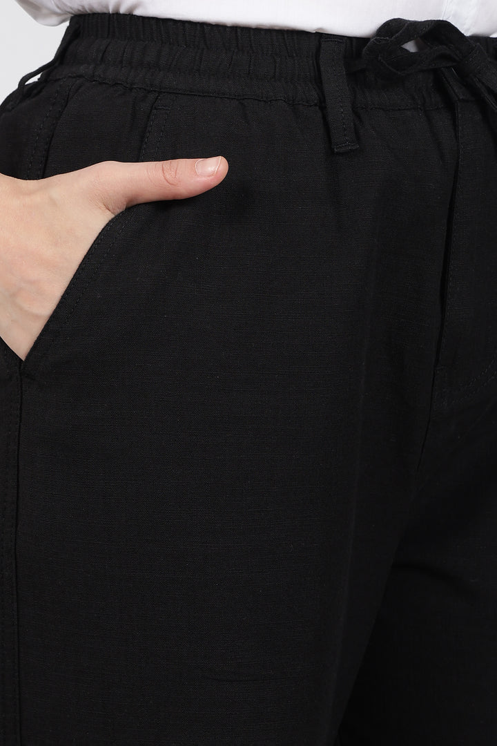 Black linen pants with a hand adjusting the waistband