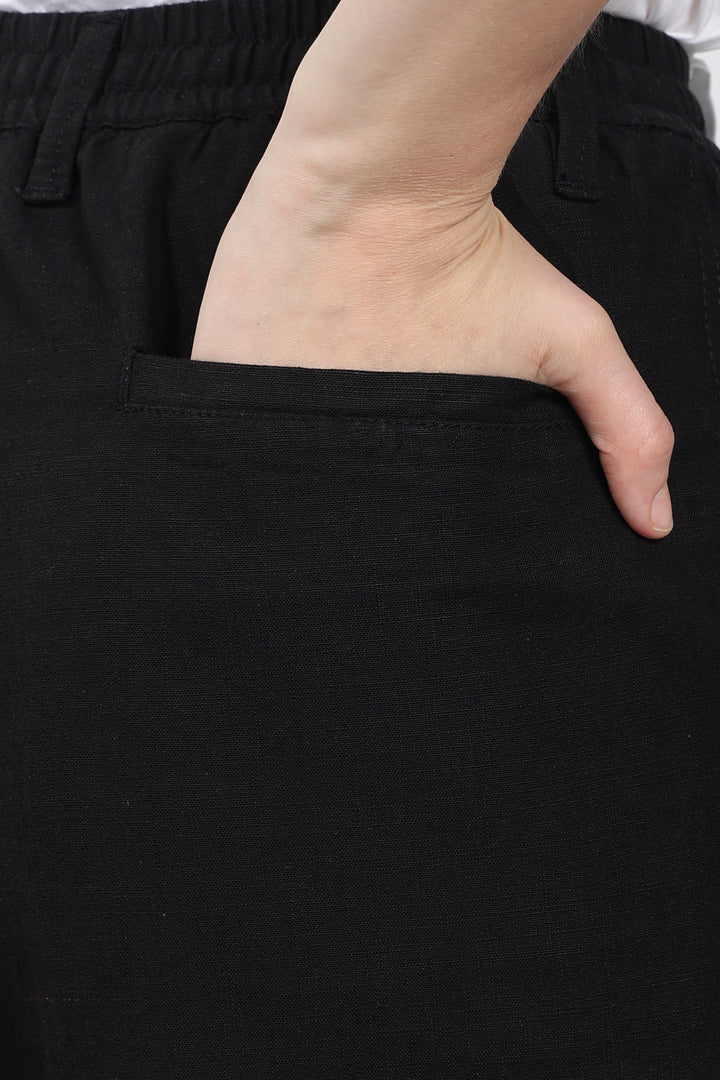 Hand in a black pocket of black linen pants