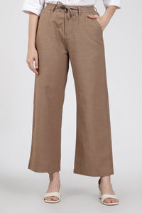 Brown wide-leg pants worn by a woman on a white background