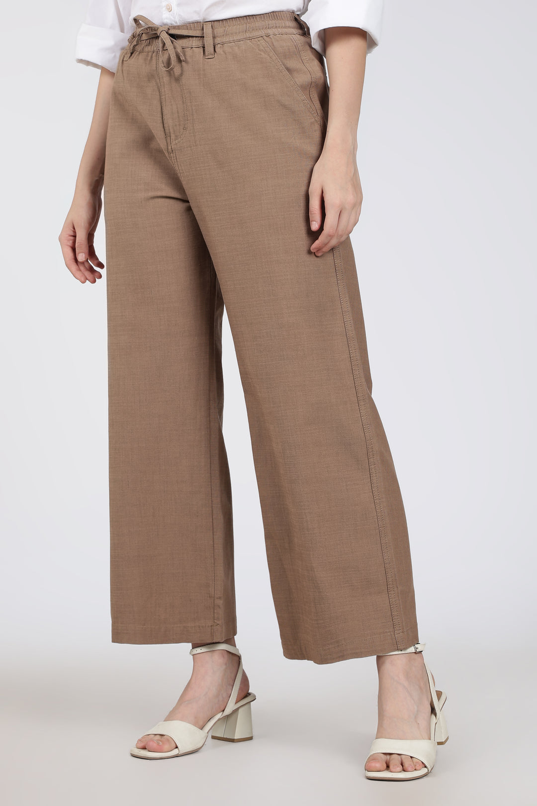 Brown wide-leg pants worn by a woman on a white background