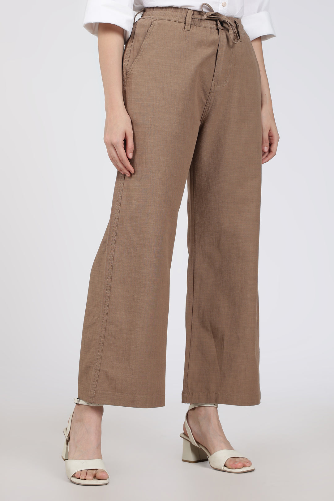 woman wearing brown pants and white shoes on a white background