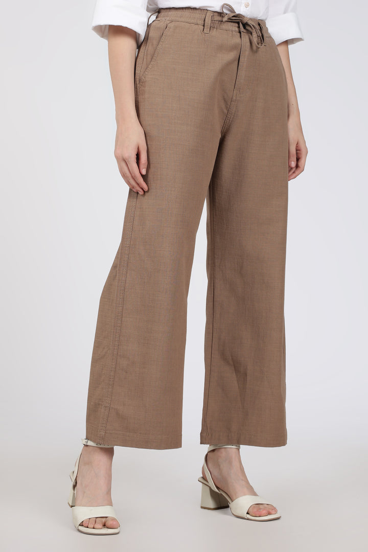 woman wearing brown pants and white shoes on a white background